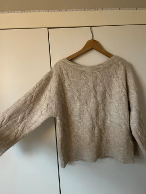 Beige stickad offshoulder tröja - Säljer en beige stickad tröja med bred ribbad kant vid halsen som kan bäras offshoulder. Tröjan har ett snyggt flätmönster och ärmar med ribbade muddar. Modellen är loose fit och ger en chill och avslappnad vibe. Perfekt för att mysa i under kyliga dagar. Ordenarie pris 299 kr från Nelly.