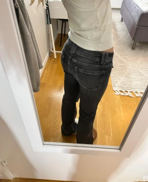 Svarta jeans  - Snygga svarta jeans med bootcut passform och låg midja. Jeansen har coola fickor med knappar framtill. 