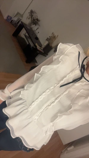 Vit volangblus - Supersöt vit blus med volanger och spetsdetaljer framtill. Knappast använd. Jättefin