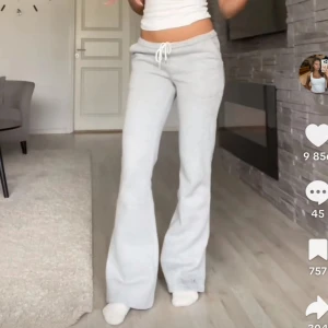 Ljusgrå bootcut mjukisbyxor med snörning - Säljer ett par ljusgrå mjukisbyxor med bootcut-snitt och dragsko i midjan. Byxorna har en avslappnad passform och är tillverkade i mjukt material som känns skönt mot huden. Perfekta för chill dagar eller när du vill vara bekväm men ändå se snygg ut.