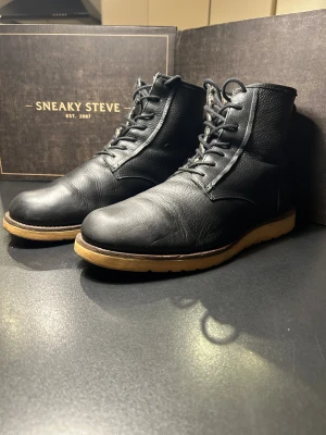 Shoe the bear svarta boots i skinn - Svarta boots från Shoe the bear med grov, ljusbrun sula och snörning framtill. Tillverkade i robust, strukturerat skinn med rund tå och klassisk siluett. Perfekt för dig som gillar stilrena och tidlösa skor med edge.