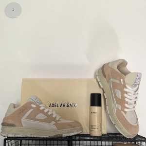 Beige sneakers från Axel Arigato - Säljer mina Axel Arigato med nypris av 3450kr, sneakers i beige/offwhite – stilrena, exklusiva och i nyskick. Endast försiktigt använda vid ett tillfälle, ser ut som nya.  Levereras med: 	•	Originalkartong 	•	Axel Arigato Protector Spray värde 170kr