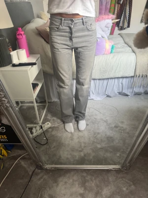 Grå raka jeans från Zara, storlek 36 - Säljer ett par grå jeans från Zara i storlek 36. De har en rak passform med normal hög midja.