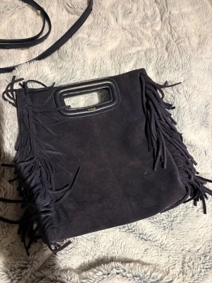 Mörkblå Maje väska - Säljer min stora mörkblåa maje väska i mocka för den inte används! Väskan kostar ca 3500 ny på hemsidan och just denna går ej att köpa längre. Dustbagen är kvar och de finns inga skador förutom den ena haken på bandet som lossnat (se bild) därav skicket, annars är allt fint ! Det går säkert att limma fast den då den kan sättas på igen men lossnar enkelt! Kan tänka mig sälja för billigare vid snabb affär!!💌🤩