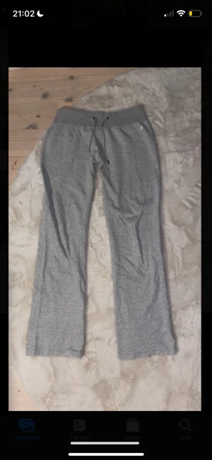 mjukisbyxor low waist - Grå mjukisbyxor från Champion, lowwaist och raka ben. Byxorna har snörning i midjan och är tillverkade i mjukt bomullsmaterial. Perfekta för chill eller träning, med diskret Champion-logga vid höften.