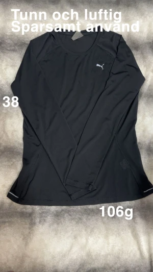 Svart långärmad träningströja Puma - Tunn och luftig svart långärmad träningströja från Puma med diskret logga på bröstet. Tillverkad i lätt polyester med meshstruktur som andas. Perfekt för aktiva dagar och sport. Snygg, enkel design med rund hals och normal passform.🌸Tunn och luftig sporttröja. Sparsamt använd. Storlek 38