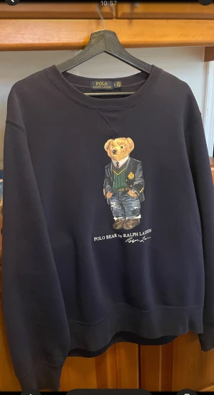 Mörkblå sweatshirt Polo Bear Ralph Lauren - Snygg mörkblå sweatshirt från Polo Ralph Lauren med ikoniskt Polo Bear-tryck på bröstet. Tröjan har rund hals, långa ärmar och en relaxed passform. Materialet är supermjuk bomull. Perfekt för dig som gillar klassisk streetstyle med en twist. Den är inte använd, endast provad.