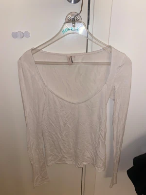 Vit långärmad topp från Nelly - Säljer en enkel och stilren vit långärmad topp från Nelly i storlek XXS. Toppen har en djup rundad urringning och är tillverkad i mjuk bomull. Perfekt att matcha med jeans eller kjol för en clean look.