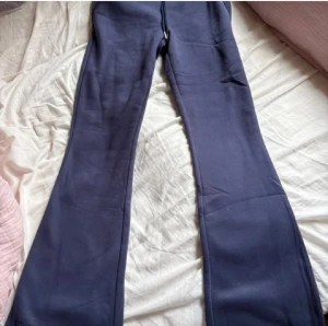 Mörkblå bootcut byxor från Nitted - Snygga mörkblå bootcut byxor från Nitted med broderad logga vid benslutet. Byxorna har en mjuk och stretchig känsla, perfekt för dig som gillar bekväma och trendiga plagg. Passformen är loose och materialet känns som bomull eller syntet.