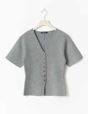Grå stickad topp med knappar Gina Tricot - Supersnygg grå stickad topp från Gina Tricot med korta ärmar och v-ringning. Toppen har en rad dekorativa knappar framtill och är figurnära i modellen. Perfekt att styla med jeans eller kjol för en clean look.