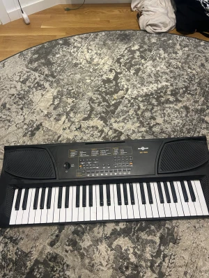 Geotamusic MK-1000 Keyboard - Elektroniskt keyboard Geotamusic MK-1000 med inbyggda högtalare, många ljud och rytmer, mikrofon och notställ medföljer. Perfekt för nybörjare och hemmabruk.