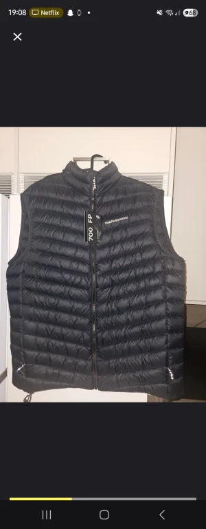 Svart dunväst från Peak Performance - Säljer en helt ny svart dunväst från Peak Performance med diskret logga på bröstet. Västen har ståkrage, quiltad design och dragkedja framtill. Perfekt för lager-på-lager och har en clean, sportig look. Modellen är lätt och har en snygg passform. Nypris 2000 kr! Byten funkar också mot jackor!