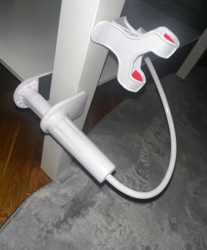 Flexibel mobilhållare  - Praktisk och flexibel mobilhållare med stark klämma för montering på bord eller sängkant. Passar de flesta smartphones. Perfekt för handsfree-användning, videovisning eller samtal. Vit färg, ser ut att vara i mycket gott skick utan synligt slitage.