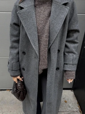 Grå kappa - Stilren grå kappa i ullmix med dubbelknäppning och breda slag. Köpt på nelly och är helt oanvänd med alla lappar kvar💌