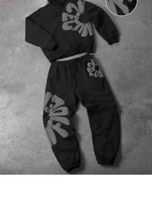 Svart loungewear set med grått tryck - Säljer ett svart loungewear set med hoodie och byxor. Setet har stora, gråa grafiska tryck på både tröjan och byxorna. Hoodien har huva och byxorna har resår i midjan och vid bensluten. Perfekt för chill dagar hemma.