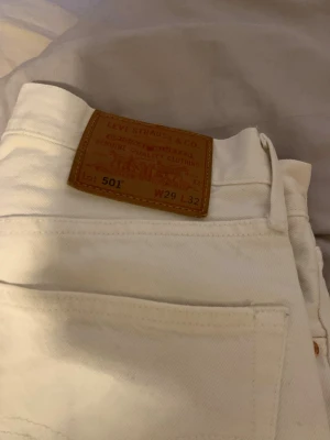 Vita Levi's 501 jeans W29 L32 - Säljer ett par klassiska vita Levi's 501 jeans med rak passform och fem fickor. Jeansen har den ikoniska läderlappen bak i midjan och är tillverkade i kraftig denim. Perfekta för dig som gillar tidlös och clean stil.