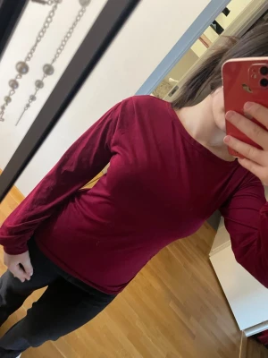 Mörkröd långärmad topp - En stilren mörkröd långärmad topp med rund halsringning. Toppen har en slim passform och är tillverkad i ett mjukt och stretchigt material som sitter snyggt på kroppen. 