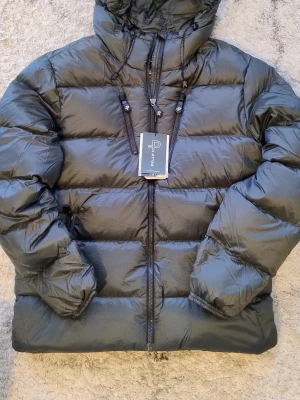 Helt ny herr dunjacka från Pelle P XL - Helt ny med prislapp på  Pelle p Dunjacka  Storlek XL Bernard Jacket 🤩 så skön och så varm dunjacka, certifierad med Responsible Down Standard (RDS).  Kostade 3590kr    Snygg grön dunjacka från Pelle P med huva och dragkedja framtill. Jackan har två sidofickor med dragkedja och justerbara snören vid huvan. Puffig modell som håller värmen bra under kalla dagar. Perfekt för vintern och riktigt stilren.