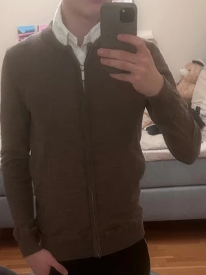 Brun ziptröja i tunn stickning - Snygg brun ziptröja i tunn stickad kvalitet med hel dragkedja framtill. Tröjan har långa ärmar och ribbade muddar vid ärmslut och nederkant. Priset är ej hugget i sten, mvh Erik