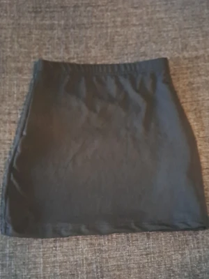 Svart kortkjol i bomull - En enkel svart kortkjol med rak passform och resår i midjan. Kjolen är tillverkad i mjuk bomull och passar perfekt till många olika stilar. Lätt att matcha med både t-shirt och skjorta.