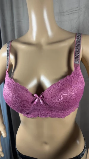 Rosa spets-bh med strassband - Snygg rosa bh i spets med vadderade kupor och dekorativ rosett framtill. Axelbanden är prydda med strass för extra bling. Perfekt för dig som gillar detaljer och vill ha något unikt. Materialet är mjuk spets och axelbanden är justerbara.