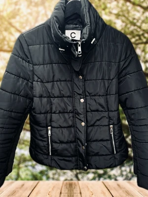 Svart pufferjacka från Cubus! - Svart figursydd pufferjacka med fickor fram, dragkedja och knappar i storlek M från Cubus. Sparsamt använd och i mycket fint skick. 