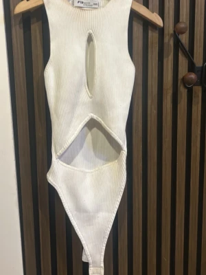 Vit ribbad baddräkt med cut-outs - Trendig vit baddräkt från Missguided i ribbat material. Modellen har högt skurna ben, cut-outs framtill och en smal passform. Perfekt för dig som vill sticka ut på stranden med en modern look.