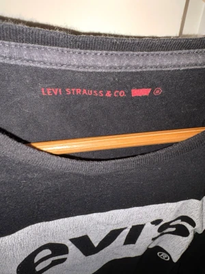 Svart Levi's t-shirt med logga - Säljer en svart t-shirt från Levi's med den klassiska vita loggan tryckt på bröstet. T-shirten har rund halsringning och korta ärmar. Perfekt för dig som gillar enkel och stilren streetwear.