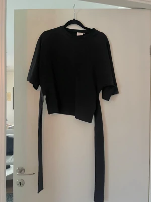 Tröja med knytning i ryggen  - Populär tröja från Nelly med knytning i ryggen.  Använd fåtal gånger  Inga anmärkningar 