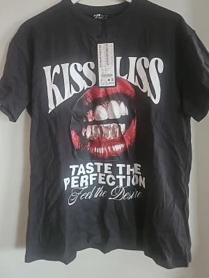 Svart t-shirt med loose fit modell. - Cool svart t-shirt med stort tryck av röda läppar och text. Loose fit modell, perfekt för dig som gillar statement-plagg.