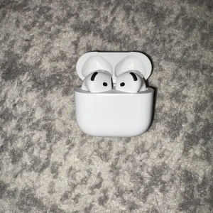 AirPods 2 - Apple AirPods 2 i originalfodral. Trådlösa hörlurar med smidig laddningsetui. Hörlurarna och fodralet är i gott skick med endast mindre spår av användning. Perfekt för musik, samtal och träning.
