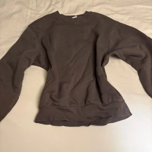 Brun sweatshirt med rund hals - Säljer en enkel brun sweatshirt med rund hals och långa ärmar. Tröjan har ribbade muddar vid ärmslut och nederkant, perfekt för chill dagar. Materialet känns mjukt och skönt mot huden.