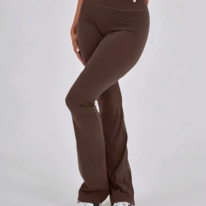 Bruna bootcut leggings med hög midja - Snygga bruna leggings med bootcut och hög midja. Stretchigt material som sitter tight över höfterna och låren, och släpper ut vid bensluten. Perfekta för dig som gillar en bekväm och trendig look. Passar till sneakers och crop tops.