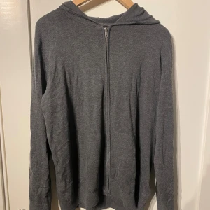 Mörkgrå hoodie med dragkedja - En enkel och stilren mörkgrå hoodie med hel dragkedja framtill och huva. Tröjan har långärmade ärmar och är gjord i mjukt material som känns skönt mot huden. 