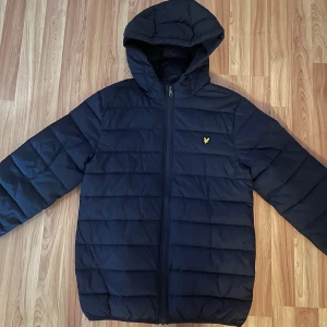 Lyle & Scott jacka  - Snygg mörkblå pufferjacka från Lyle & Scott med huva och dragkedja framtill. Den perfekta vinterjackan, storlek 15/16år skulle säga att den motsvarar en S/M kanske. Skick 10/10 eftersom jag aldrig använt den bara testat. Pris kan diskuteras lite vid snabb affär!