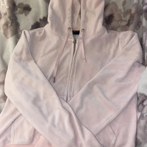 JUICY SET BÅDA BYXAN OCH TRÖJAN! - Supermjuk ljusrosa hoodie från Juicy Couture i klassisk velour. Tröjan har dragkedja, huva med snörning och broderad JC-logga på bröstet. Perfekt för en chill och trendig look.