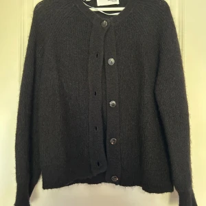 Svart stickad kofta från Selected Femme - Svart stickad kofta från Selected Femme med rund halsringning och knappar framtill. Nypris är 699kr. 