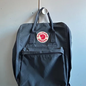 Svart Fjällräven Kånken Laptop 17" ryggsäck -  Fjällräven Kånken Laptop 17" ryggsäck i färgen Navy. Ryggsäcken har ett stort huvudfack, vadderat laptopfack, framficka med dragkedja och två sidofickor. Jättesmidig och rymlig, med bärhandtag och justerbara axelremmar. Säljer för att jag inte har någon användning för den. Nypris 1799 kr