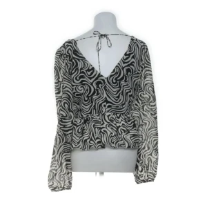 Zebramönstrad blus från H&M XS - Säljer en svartvit zebramönstrad blus från H&M i storlek XS. Blusen har långärmade, transparenta ärmar, v-ringning både fram och bak samt knytband i nacken. Materialet är lätt och luftigt, perfekt för att sticka ut med ett coolt mönster.