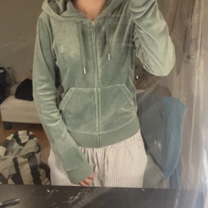 Juicy Couture grön velour hoodie - Mjuk grön hoodie i velour från Juicy Couture med dragkedja och klassisk huva. J:et är lite trasigt (bild 2)