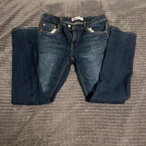 Levi's 512 Slim Taper jeans blå st 176 cm - Snygga Levi's 512 Slim Taper jeans i klassisk blå tvätt med kontrasterande orange sömmar. Modellen har fem fickor, smal passform och avsmalnande ben. Perfekt för dig som gillar en modern och stilren look. Jeansmaterialet är slitstarkt och bekvämt.