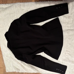 Svart kavaj från InWear - Klassisk svart kavaj från Inwear med två knappar framtill, smala slag och innerfoder med diskret mönster. Kavajen har fickor med lock och fyra knappar vid ärmslutet. Snygg och tidlös modell som ger en clean look.