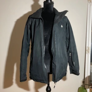Svart vinterjacka - Svart vinterjacka, luvan saknas. Längd ca 70cm. Ärmlängd ca 55cm. Pris: 20kr 