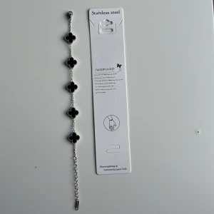 Black-silver alhambra bracelet - Stilrent armband i rostfritt stål med fem svarta klöverformade hängen. Kedjan är silverfärgad och har justerbar längd. Perfekt för dig som gillar detaljer med lite edge och vill sticka ut med en cool accessoar. Mvh clover.se