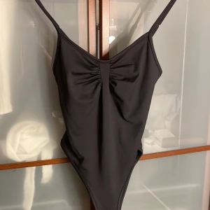 Svart body - Snygg svart body med smala axelband och rynkdetalj framtill. Enkel och stilren design som ger en clean look, med justerbara axelband för bästa passform.