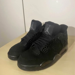 Svarta Nike Air Jordan 4 sneakers - Säljer ett par helsvarta Nike Air Jordan 4 sneakers med klassisk mesh och detaljer i mocka. Skorna har snörning, rund tå och ikoniska Jumpman-loggor på plös och häl. Perfekta för dig som vill ha en clean och stilren look. Låda finns oanvända!