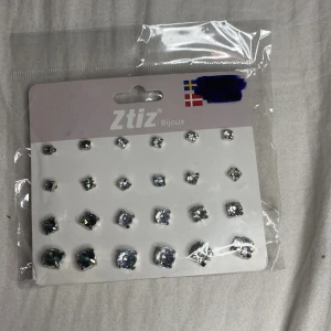 Set med silvriga örhängen från Ztiz - Flera par örhängen från Ztiz i olika storlekar med glittriga stenar i silver och mörkgrå nyanser. Klassisk rund form och infattning i silvrig metall. Perfekt för att mixa och matcha till olika looks.