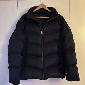 GANT The Alta down jacket  - Snygg och varm mörkblå dunjacka från GANT med dragkedja framtill. Perfekt för kyliga dagar. Den är i storlek M och nypris är 2500 kr.