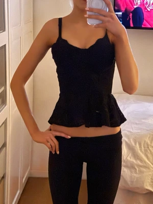 Svart korsettopp med volangkant och spets  - Assnygg festtopp med spets. Ej genomskinlig och passar perfekt till när man vill klä upp sig eller till sommaren!! Toppen har inga axelband men sitter uppe bra oavsett!! Den är köpt på BIKBOK och är i storlek S men den passar XS också.
