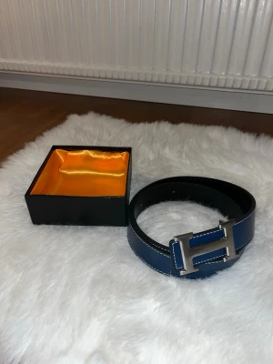 Mörkblå Herme’s Skinn bälte - Säljer denna Mörkblåa Skinn bälte med H spänne. Dens storlek är 110cm. Den är helt nya inga defekter men har en extra hål.